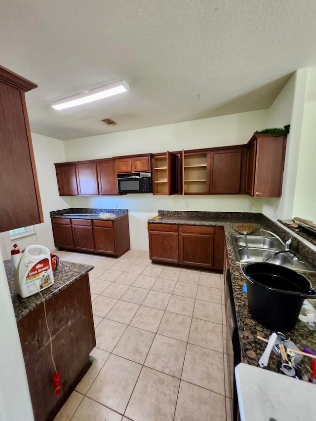 1015 Amaryllis Rd, Baytown, TX 77521 - kitchen with black microwave, open shelves, light tile patterned flooring, a textured ceiling, and dark stone countertops