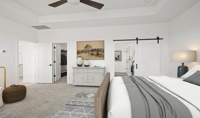 6220 Pelican Ridge Way, League City, TX 77573 - bedroom featuring light carpet, a tray ceiling, a spacious closet, a barn door, and a closet