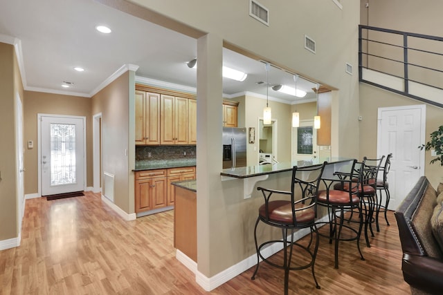 81 Baron Dr, Coldspring, TX 77331 - kitchen with a kitchen bar, stainless steel fridge with ice dispenser, light wood finished floors, crown molding, and backsplash
