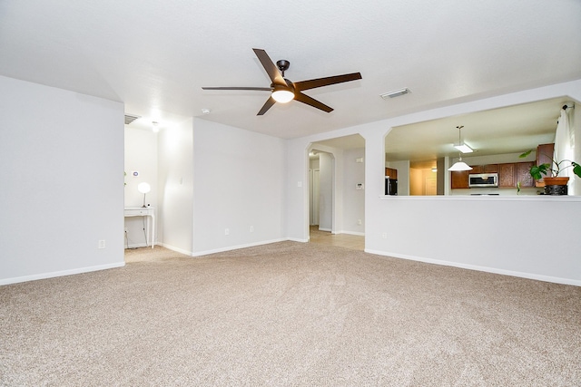 2739 Mustang Hill Ln, Katy, TX 77449 - unfurnished living room featuring a ceiling fan, light colored carpet, arched walkways, and baseboards
