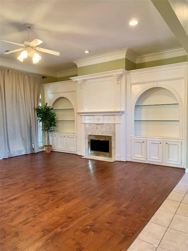 8303 Lanham Ln, Houston, TX 77075 - unfurnished living room featuring built in features, crown molding, ceiling fan, a high end fireplace, and wood finished floors