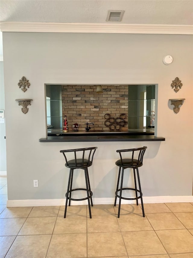8303 Lanham Ln, Houston, TX 77075 - dining area with ornamental molding, bar with sink, light tile patterned flooring, and baseboards