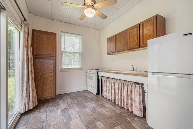 18751 Julie Ln, Magnolia, TX 77355 - kitchen with white appliances, brown cabinetry, a ceiling fan, a sink, and wood finished floors