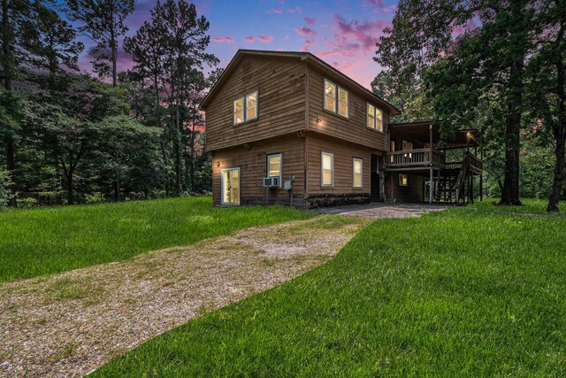 18751 Julie Ln, Magnolia, TX 77355 - property exterior at dusk with a deck, a patio area, a lawn, and stairs