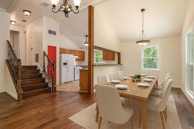 18751 Julie Ln, Magnolia, TX 77355 - dining area with dark wood finished floors, a chandelier, stairs, baseboards, and high vaulted ceiling