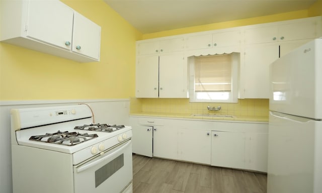 4915 Walker St, Houston, TX 77023 - kitchen with white appliances, tile countertops, white cabinets, light wood finished floors, and tasteful backsplash