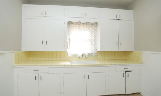 4915 Walker St, Houston, TX 77023 - kitchen with decorative backsplash, a sink, and white cabinets