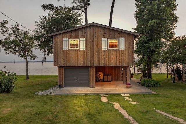 784 W Cattle Dr, Onalaska, TX 77360 - outdoor structure at dusk with a yard, a garage, and a water view