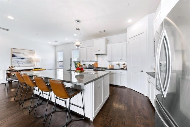 1822 Mcilhenny St Unit B, Houston, TX 77004 - kitchen with freestanding refrigerator, dark wood-style flooring, white cabinetry, a breakfast bar area, and a kitchen island with sink