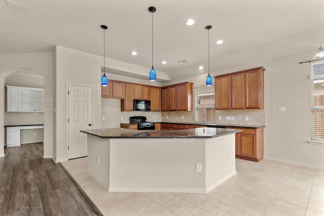 12906 Leafy Shores Dr, Houston, TX 77044 - kitchen featuring black appliances, arched walkways, brown cabinetry, backsplash, and a center island
