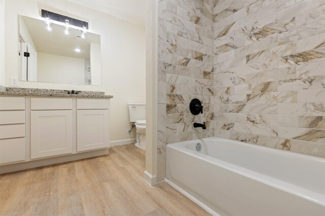 2801 Pickerton Dr, Deer Park, TX 77536 - bathroom featuring toilet, wood finished floors, vanity, baseboards, and tub / shower combination