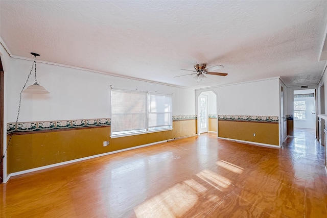 31002 Misty Meadow Dr, Magnolia, TX 77354 - empty room featuring wainscoting, ceiling fan, a textured ceiling, baseboards, and arched walkways