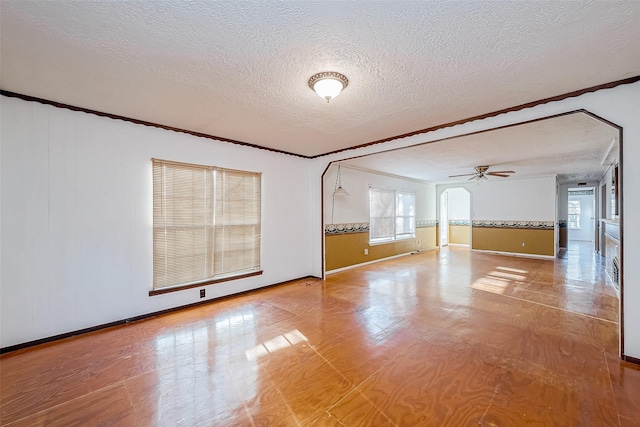 31002 Misty Meadow Dr, Magnolia, TX 77354 - empty room with crown molding, a textured ceiling, baseboards, arched walkways, and a ceiling fan
