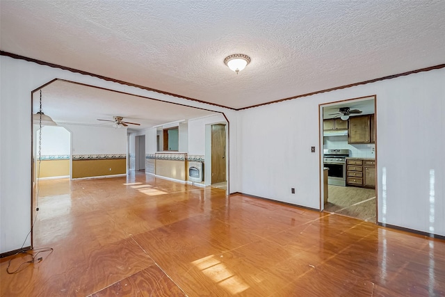 31002 Misty Meadow Dr, Magnolia, TX 77354 - unfurnished living room with a ceiling fan, ornamental molding, baseboards, a textured ceiling, and arched walkways
