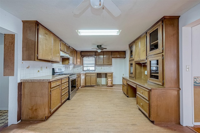31002 Misty Meadow Dr, Magnolia, TX 77354 - kitchen with stainless steel range with gas cooktop, a ceiling fan, under cabinet range hood, and light wood finished floors