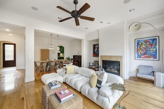 2306 Mcduffie St, Houston, TX 77019 - living room featuring a ceiling fan, light wood-style floors, a tile fireplace, ornamental molding, and recessed lighting