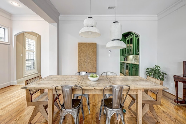 2306 Mcduffie St, Houston, TX 77019 - dining area with arched walkways, ornamental molding, light wood-type flooring, baseboards, and wine cooler