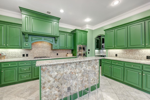 2306 Mcduffie St, Houston, TX 77019 - kitchen with stainless steel appliances, arched walkways, decorative backsplash, crown molding, and light stone countertops
