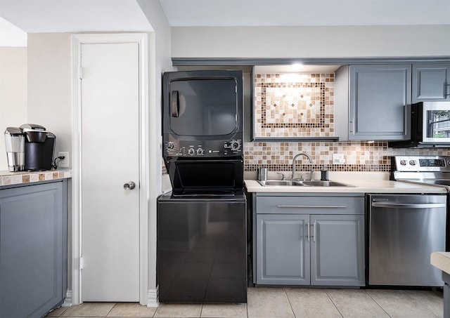 2011 Winrock Blvd Unit 172, Houston, TX 77057 - kitchen with stainless steel appliances, stacked washer / drying machine, a sink, gray cabinetry, and backsplash