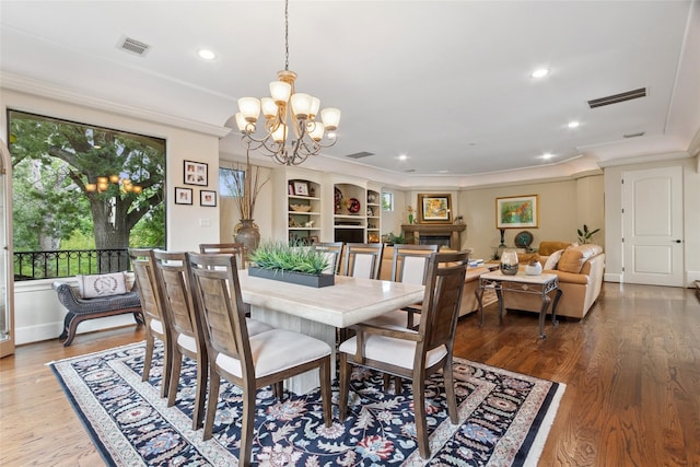 5520 Mcculloch Cir, Houston, TX 77056 - dining space with crown molding, a chandelier, a fireplace, wood finished floors, and recessed lighting