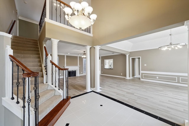 42 Stalybridge St, Sugar Land, TX 77479 - entryway with decorative columns, a chandelier, a fireplace, tile patterned flooring, and stairway