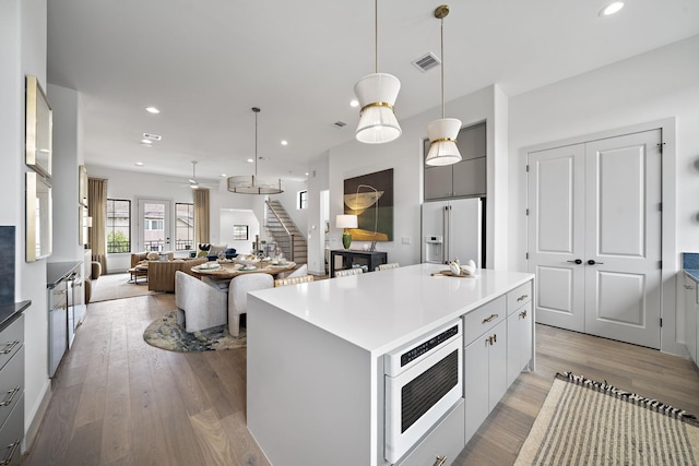 1720 Sedola Ln, Houston, TX 77055 - kitchen with high quality fridge, light wood-type flooring, gray cabinets, hanging light fixtures, and open floor plan
