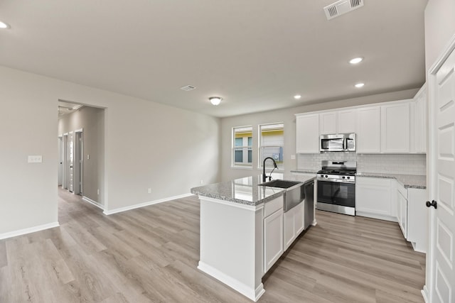 18810 Lucas Michael Way, New Caney, TX 77357 - kitchen featuring appliances with stainless steel finishes, a sink, recessed lighting, decorative backsplash, and a center island with sink
