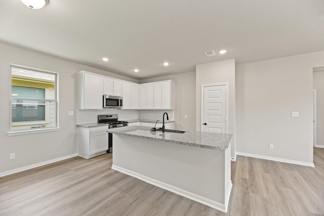 18810 Lucas Michael Way, New Caney, TX 77357 - kitchen featuring stainless steel appliances, a sink, light wood finished floors, white cabinets, and recessed lighting