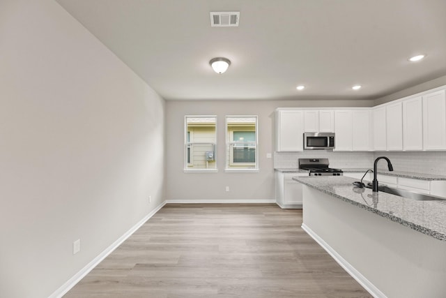 18810 Lucas Michael Way, New Caney, TX 77357 - kitchen featuring stainless steel appliances, a sink, decorative backsplash, white cabinets, and recessed lighting