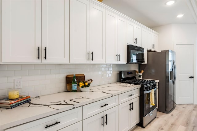 4014 Linder St, Houston, TX 77026 - kitchen featuring gas range oven, black microwave, white cabinetry, light wood-style flooring, and decorative backsplash