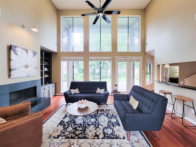 4900 Willow St, Bellaire, TX 77401 - living room with a towering ceiling, wood finished floors, a tiled fireplace, ceiling fan, and baseboards