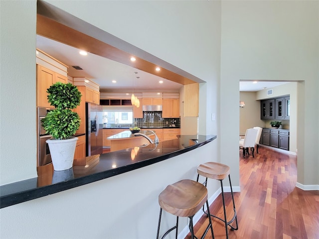 4900 Willow St, Bellaire, TX 77401 - kitchen featuring appliances with stainless steel finishes, wood finished floors, light brown cabinetry, decorative backsplash, and recessed lighting