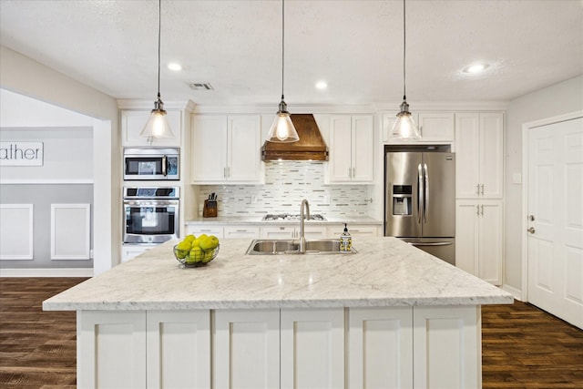 11102 Hillcroft St, Houston, TX 77096 - kitchen featuring appliances with stainless steel finishes, custom exhaust hood, white cabinetry, a center island with sink, and recessed lighting