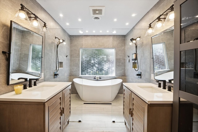 11102 Hillcroft St, Houston, TX 77096 - bathroom featuring tile walls, two vanities, a soaking tub, and recessed lighting
