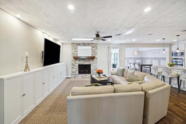 11102 Hillcroft St, Houston, TX 77096 - living room with a ceiling fan, dark wood-style flooring, a stone fireplace, and recessed lighting