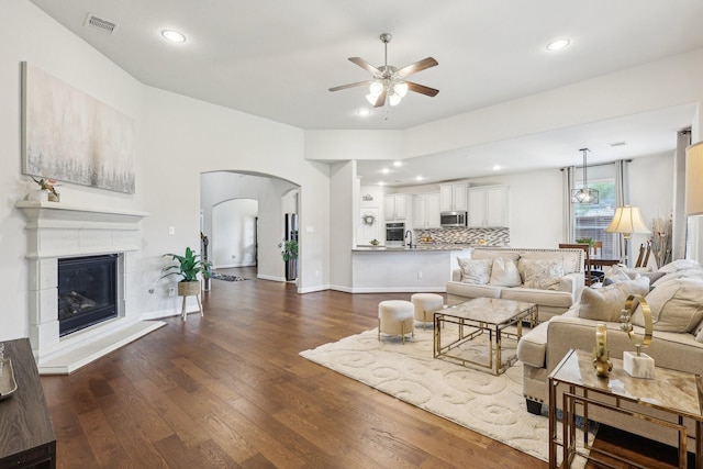 3403 Majestic Pine Ln, Rosenberg, TX 77471 - living room featuring a ceiling fan, arched walkways, dark wood-style flooring, recessed lighting, and a glass covered fireplace
