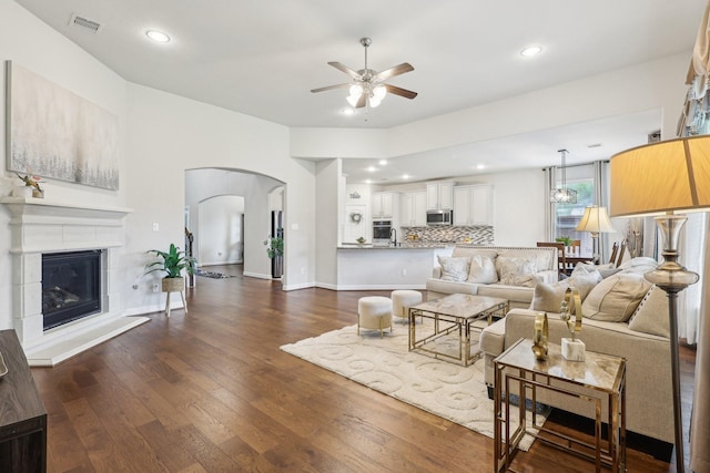 3403 Majestic Pine Ln, Rosenberg, TX 77471 - living area featuring a ceiling fan, arched walkways, dark wood-style floors, recessed lighting, and a glass covered fireplace