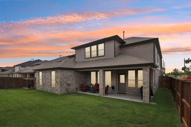 3403 Majestic Pine Ln, Rosenberg, TX 77471 - back of property at dusk featuring brick siding, a patio, and a shingled roof
