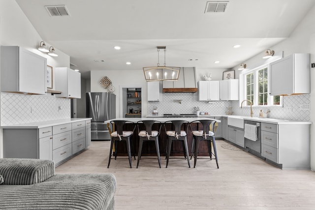 50 Berry St, Coldspring, TX 77331 - kitchen featuring stainless steel appliances, gray cabinetry, tasteful backsplash, a kitchen bar, and premium range hood