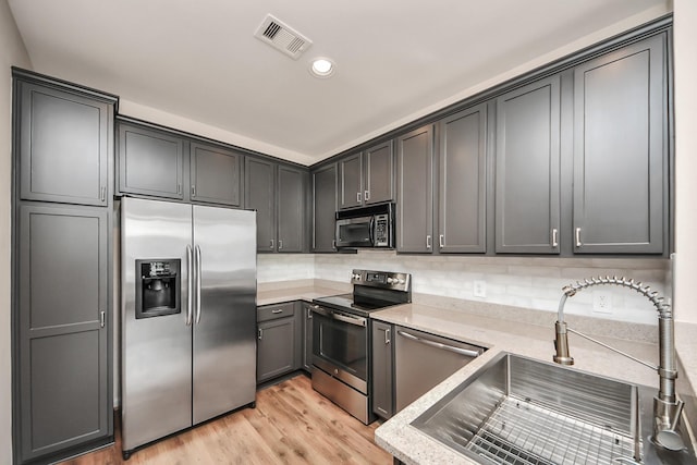 3001 Murworth Dr Unit 103, Houston, TX 77025 - kitchen featuring appliances with stainless steel finishes, a sink, light wood-style flooring, decorative backsplash, and recessed lighting