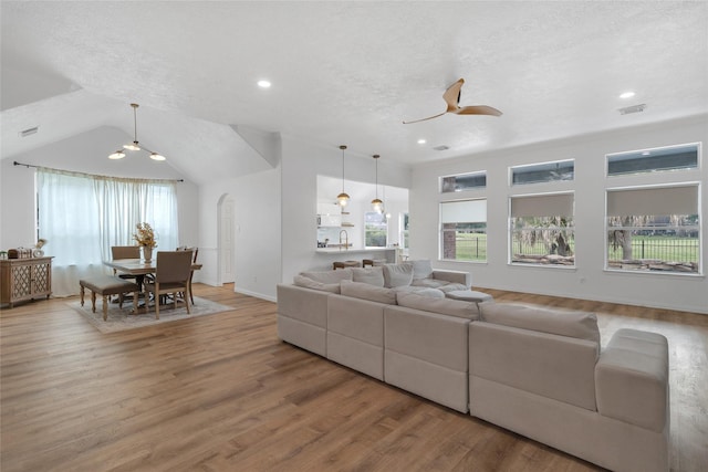 18327 Marlin Waters Dr, Humble, TX 77346 - living room with ceiling fan, light wood-style flooring, baseboards, arched walkways, and a textured ceiling
