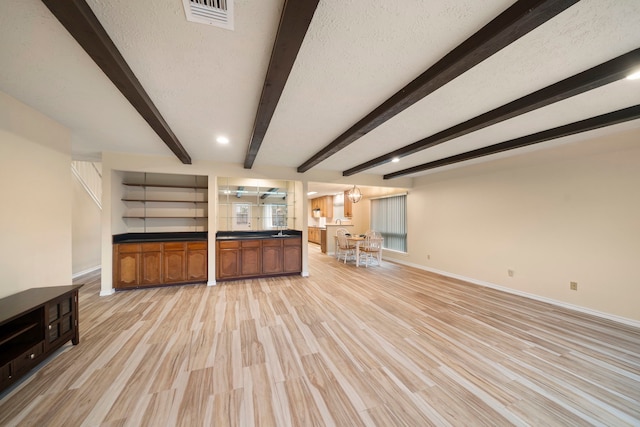 2311 Jackson Ln, League City, TX 77573 - unfurnished living room featuring beam ceiling, baseboards, light wood-style flooring, and a textured ceiling