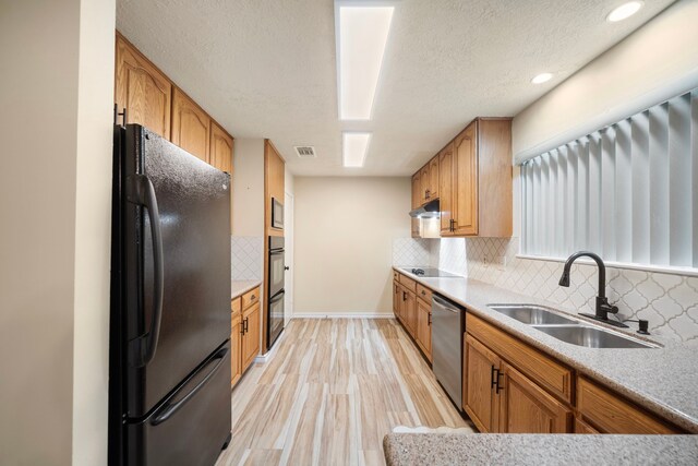 2311 Jackson Ln, League City, TX 77573 - kitchen featuring black appliances, a sink, baseboards, decorative backsplash, and light wood-style flooring