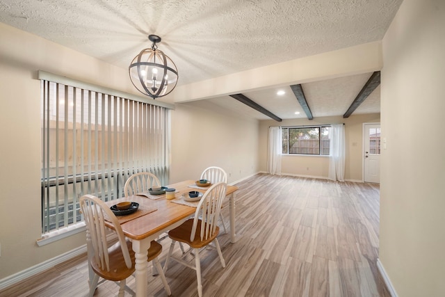 2311 Jackson Ln, League City, TX 77573 - dining room with baseboards, light wood-type flooring, a chandelier, beam ceiling, and a textured ceiling