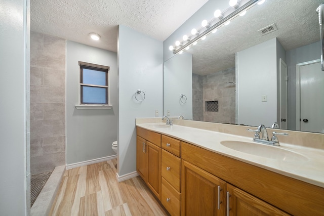 2311 Jackson Ln, League City, TX 77573 - full bathroom featuring double vanity, walk in shower, toilet, a textured ceiling, and wood finished floors