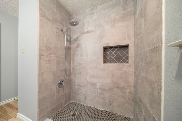 2311 Jackson Ln, League City, TX 77573 - bathroom with a textured ceiling, a tile shower, wood finished floors, and baseboards