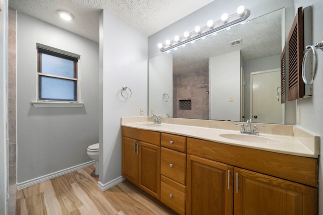 2311 Jackson Ln, League City, TX 77573 - bathroom with double vanity, toilet, wood finished floors, baseboards, and a textured ceiling