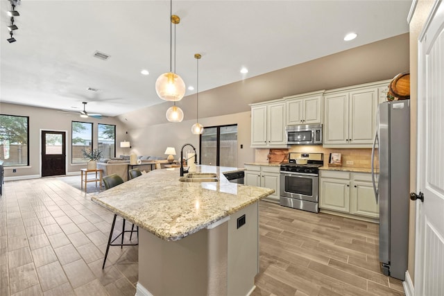 24747 Ballad Dr, Katy, TX 77493 - kitchen with appliances with stainless steel finishes, a sink, open floor plan, light wood-type flooring, and a kitchen bar
