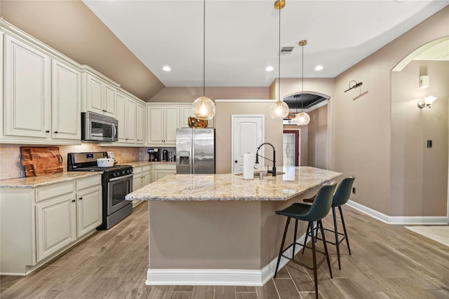 24747 Ballad Dr, Katy, TX 77493 - kitchen with appliances with stainless steel finishes, arched walkways, baseboards, light wood-style flooring, and a sink
