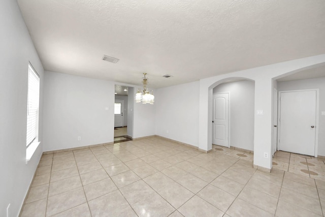 4310 Lucas Trace Ct, Houston, TX 77066 - spare room with light tile patterned floors, a chandelier, a textured ceiling, arched walkways, and baseboards